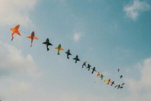 A string of brightly coloured kites fly in the sky