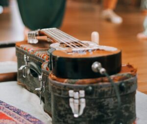 A guitar sits on a guitar case as people dance in the background