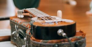 A guitar sits on a guitar case as people dance in the background